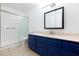 Well-lit bathroom featuring a tiled shower, toilet, and blue vanity with ample counter space and storage at 1050 Morgan Ln, Pahrump, NV 89060