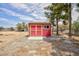 Red shed with tan trim sits in a spacious lot with trees and blue sky at 1050 Morgan Ln, Pahrump, NV 89060