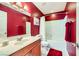 A red-themed bathroom with cherry vanity, sink, mirror, tub and toilet at 10725 Wrigley Field Ave, Las Vegas, NV 89166