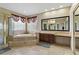Bright bathroom with soaking tub, glass shower, travertine floors, and vanity with granite counters at 2010 Catalina Marie Ave, Henderson, NV 89074