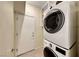 Well-lit laundry room including a stacked washer and dryer set with storage shelving and a door to outside at 2154 Idaho Falls Dr, Henderson, NV 89044