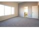 Spacious bedroom with large windows and neutral carpet and paint tones, bathroom door visible at 3412 Adventure Ct, Las Vegas, NV 89129