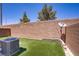 Enclosed backyard featuring artificial grass, a brick wall, and an AC unit at 4020 Smokey Fog Ave # 3, North Las Vegas, NV 89081