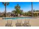 A community pool with lounge chairs surrounded by lush landscaping and palm trees for relaxation at 4020 Smokey Fog Ave # 3, North Las Vegas, NV 89081