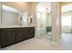 Spacious bathroom featuring a large mirror, dark cabinets, and a walk-in shower at 4630 Blushing Dawn Ave, Las Vegas, NV 89118