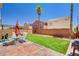 Well-maintained backyard featuring a patio with outdoor furniture, lush turf, and mature palm trees for added privacy at 5516 Tantalum Ln, Las Vegas, NV 89122