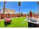 Charming backyard featuring synthetic grass, patio seating, and a swing set, perfect for Gathering fun in the sun at 5516 Tantalum Ln, Las Vegas, NV 89122