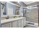 This bathroom is equipped with a double sink, granite countertop, large framed mirror, and tiled shower with glass door at 5516 Tantalum Ln, Las Vegas, NV 89122