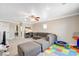Spacious bonus room featuring a comfortable gray sofa, ceiling fan, and designated ' play area at 5516 Tantalum Ln, Las Vegas, NV 89122