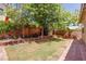 Landscaped backyard with healthy lawn, mature trees, and decorative brick features at 5896 Shining Moon Ct, Las Vegas, NV 89131