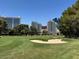 Well manicured golf course with sand traps, lush greenery, and towering buildings in the background at 632 Tam O Shanter, Las Vegas, NV 89109