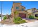 Tan two-story home featuring a two-car garage, surrounded by desert landscaping for a low-maintenance yard at 7730 Moore Creek Ln, North Las Vegas, NV 89084