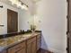 Bathroom vanity featuring granite countertops and wood cabinets, paired with modern lighting fixtures at 8010 Palm Cove Ct, Las Vegas, NV 89129