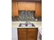 Kitchen sink featuring wood cabinets and tiled backsplash in neutral colors at 925 Falconhead Ln # 102, Las Vegas, NV 89128