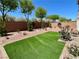 Backyard featuring artificial turf, desert landscaping, and a brick retaining wall at 9853 Russian Hill St, Las Vegas, NV 89141