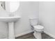 White pedestal sink and toilet in minimalist bathroom with dark wood-look flooring at 10013 Sable Point St, Las Vegas, NV 89178