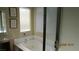 Bright bathroom featuring a soaking tub with jets, a shower with glass doors, and neutral tones at 1504 Andrew David Ave, North Las Vegas, NV 89086