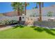 Wonderful backyard with a climbing wall, playhouse, lush artificial turf, and mature palm trees at 189 Andada Dr, Henderson, NV 89012