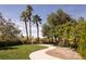 Serene backyard featuring a lush green lawn, mature trees, and a winding walkway at 2041 Troon Dr, Henderson, NV 89074