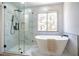 Bright bathroom featuring a soaking tub, walk-in shower, and marble-patterned tile at 2204 Brighton Shore St, Las Vegas, NV 89128