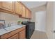 Laundry room with washer, dryer, sink, wooden cabinets and tile flooring at 2385 Orangeburg Pl, Henderson, NV 89044
