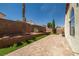 Private backyard featuring a large brick patio, tiered landscaping, and partial synthetic grass at 3597 Cherbourg Ave, Las Vegas, NV 89141