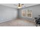 Bright bedroom with ceiling fan, two windows, and soft carpet flooring at 390 Clarence House Ave # 1, North Las Vegas, NV 89032