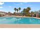 Community pool area with lounge chairs, umbrellas, and palm trees on a sunny day at 390 Clarence House Ave # 1, North Las Vegas, NV 89032