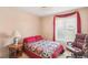 Comfortable bedroom with a quilt, an office chair and a window with red curtains at 4027 Maple Hill Rd, Las Vegas, NV 89115
