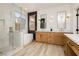 Bright bathroom featuring double vanity, soaking tub, and glass shower with modern fixtures and wood-look tile floors at 4493 Rometta Ave, Las Vegas, NV 89141