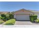 Beige one-story home with a two-car garage, desert landscaping and a tile roof under a clear blue sky at 4672 Regalo Bello St, Las Vegas, NV 89135