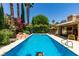Stunning backyard pool with mature landscaping, rock waterfall, and shaded seating area for relaxation at 5133 Southern Hills Ln, Las Vegas, NV 89113