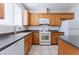 Kitchen with wooden cabinets, white appliances, tile floors, and black granite countertops at 5938 Village Loft St, North Las Vegas, NV 89081