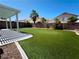 Large backyard with artificial turf, covered patio, and well-maintained landscaping at 6608 Buried Treasure Ct, Las Vegas, NV 89139