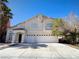 Two-story home with a stucco facade, arched entry, and an attached two-car garage at 6608 Buried Treasure Ct, Las Vegas, NV 89139