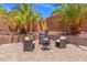 Backyard patio with a charming firepit, seating area, and mature palm trees at 6958 Lazy Sunset Ct, Las Vegas, NV 89156