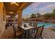 Charming covered patio with dining set overlooking a sparkling pool and landscaped backyard at 6958 Lazy Sunset Ct, Las Vegas, NV 89156