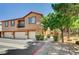 Charming exterior view of tan townhouse with a small balcony and green shrubbery at 9115 Canoga Canyon Ct # 103, Las Vegas, NV 89149