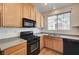 Well-lit kitchen with wood cabinetry, speckled countertops, and modern black appliances at 9115 Canoga Canyon Ct # 103, Las Vegas, NV 89149