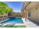 A backyard pool with a waterfall feature, a covered patio, and a clear blue sky at 9784 Kodiak Island Ct, Las Vegas, NV 89141