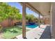 Backyard pool with a waterfall feature, a small lawn, and a covered patio at 9784 Kodiak Island Ct, Las Vegas, NV 89141
