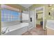 Bathroom showcasing a soaking tub with tile surround, a separate shower, and a view of the closet at 9909 Masked Duck Ave, Las Vegas, NV 89117