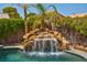 Resort style pool featuring a stone waterfall and lush landscaping offering a private backyard oasis at 9909 Masked Duck Ave, Las Vegas, NV 89117