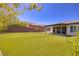Well-manicured backyard with artificial turf, desert landscaping, and a covered patio area for outdoor living at 10349 Bressana Dr, Las Vegas, NV 89135