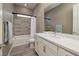 Bright bathroom with a shower-tub, large mirror, gray wood-look floors and marble countertops at 10349 Bressana Dr, Las Vegas, NV 89135