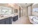 Elegant bathroom with dual vanities, a glass-enclosed shower, and a luxurious soaking tub at 11219 Playa Bonita Ave, Las Vegas, NV 89138