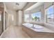 Luxurious bathroom featuring tiled floors, a soaking tub, and bright natural lighting at 11219 Playa Bonita Ave, Las Vegas, NV 89138