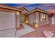 Close-up of a home's front entrance featuring rock landscaping, a security gate, and warm exterior lighting at 1643 Silver Slipper Ave, Henderson, NV 89002