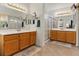 Bathroom with dual vanities, wood cabinets, and a glass shower at 1870 Desert Forest Way, Henderson, NV 89012