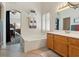 Bright bathroom featuring a tub, shuttered window and a vanity with wood cabinets at 1870 Desert Forest Way, Henderson, NV 89012